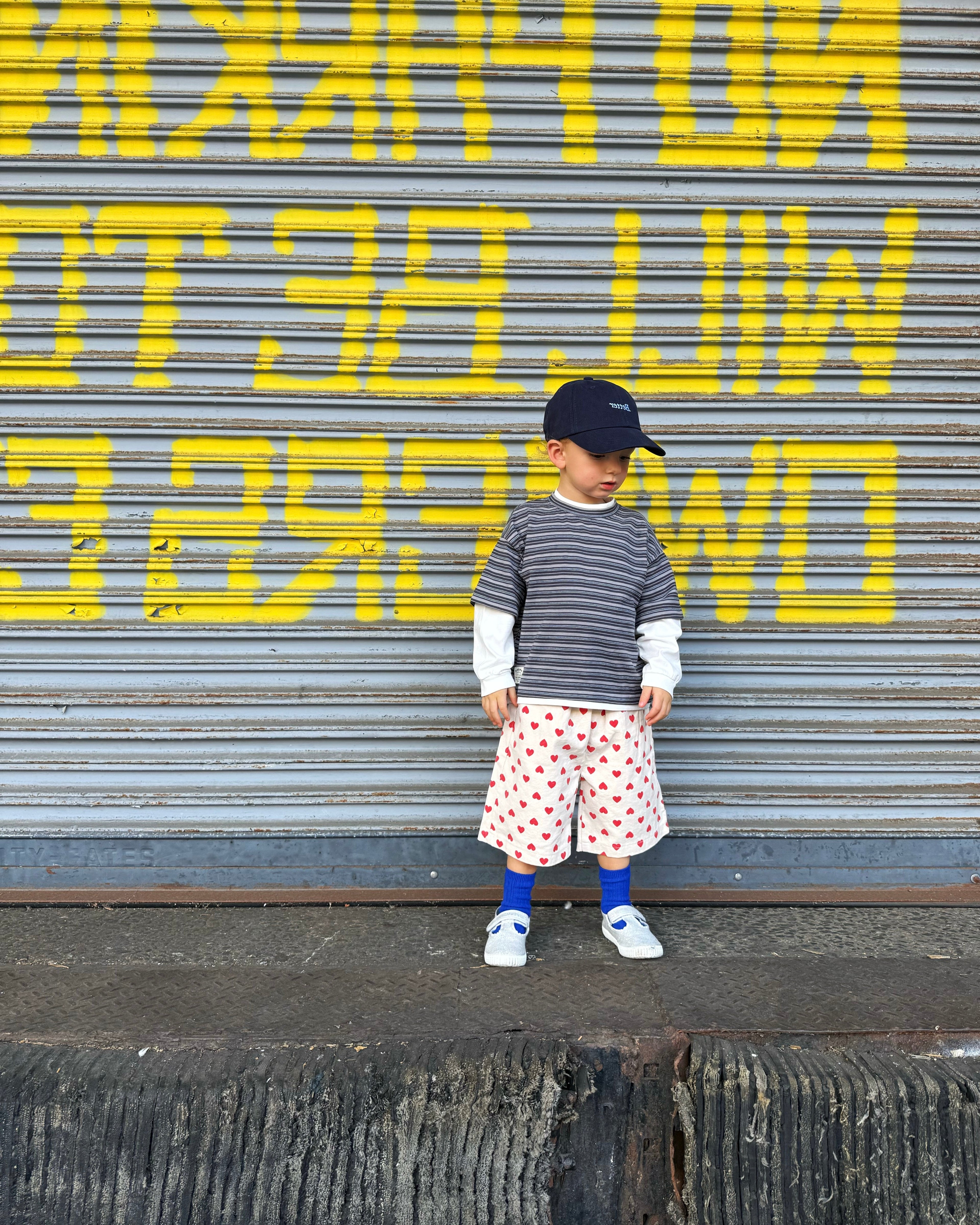 Child standing in front of a garage wearing a cool street style outfit. 