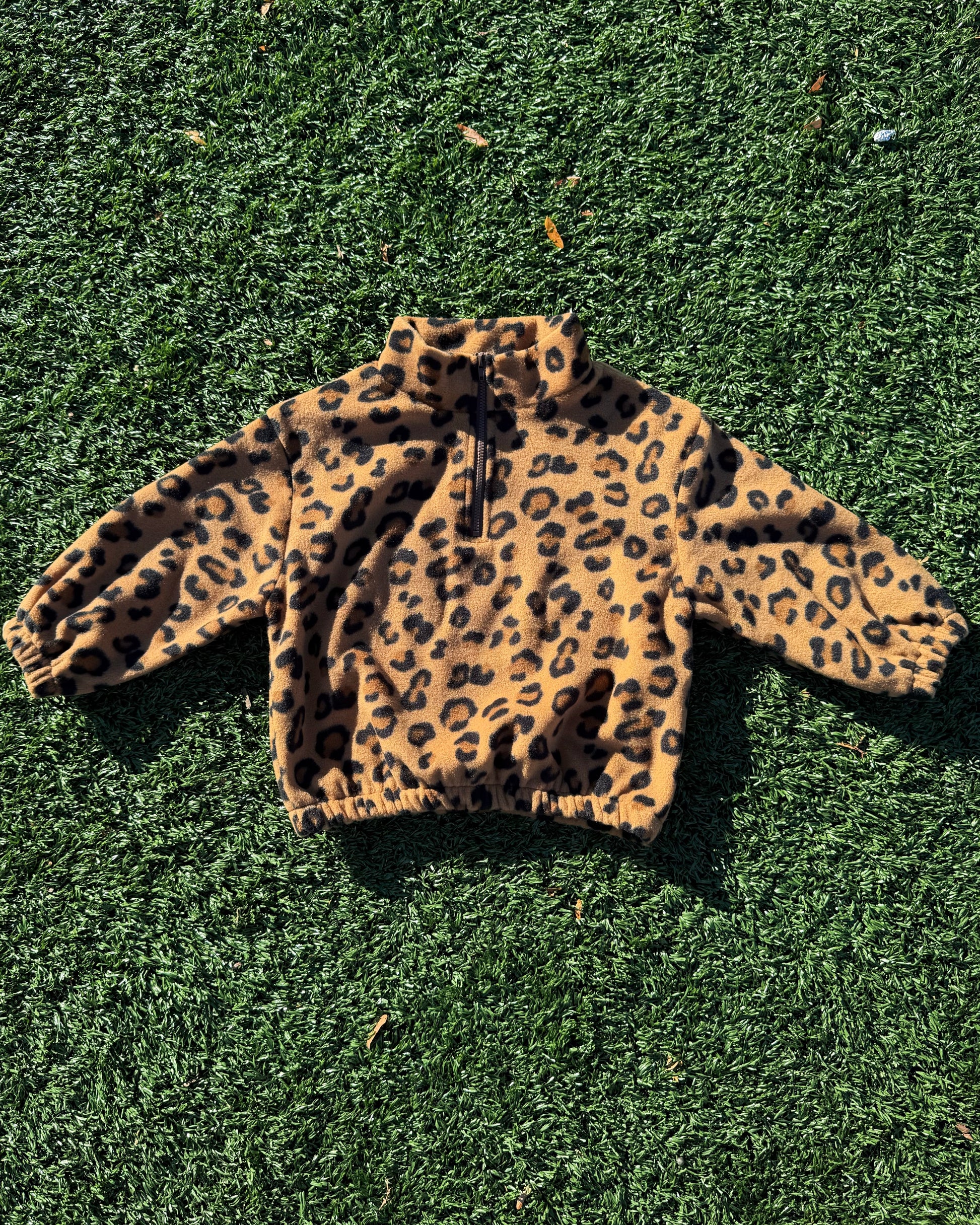 Kids leopard print fleece jacket on a grassy surface