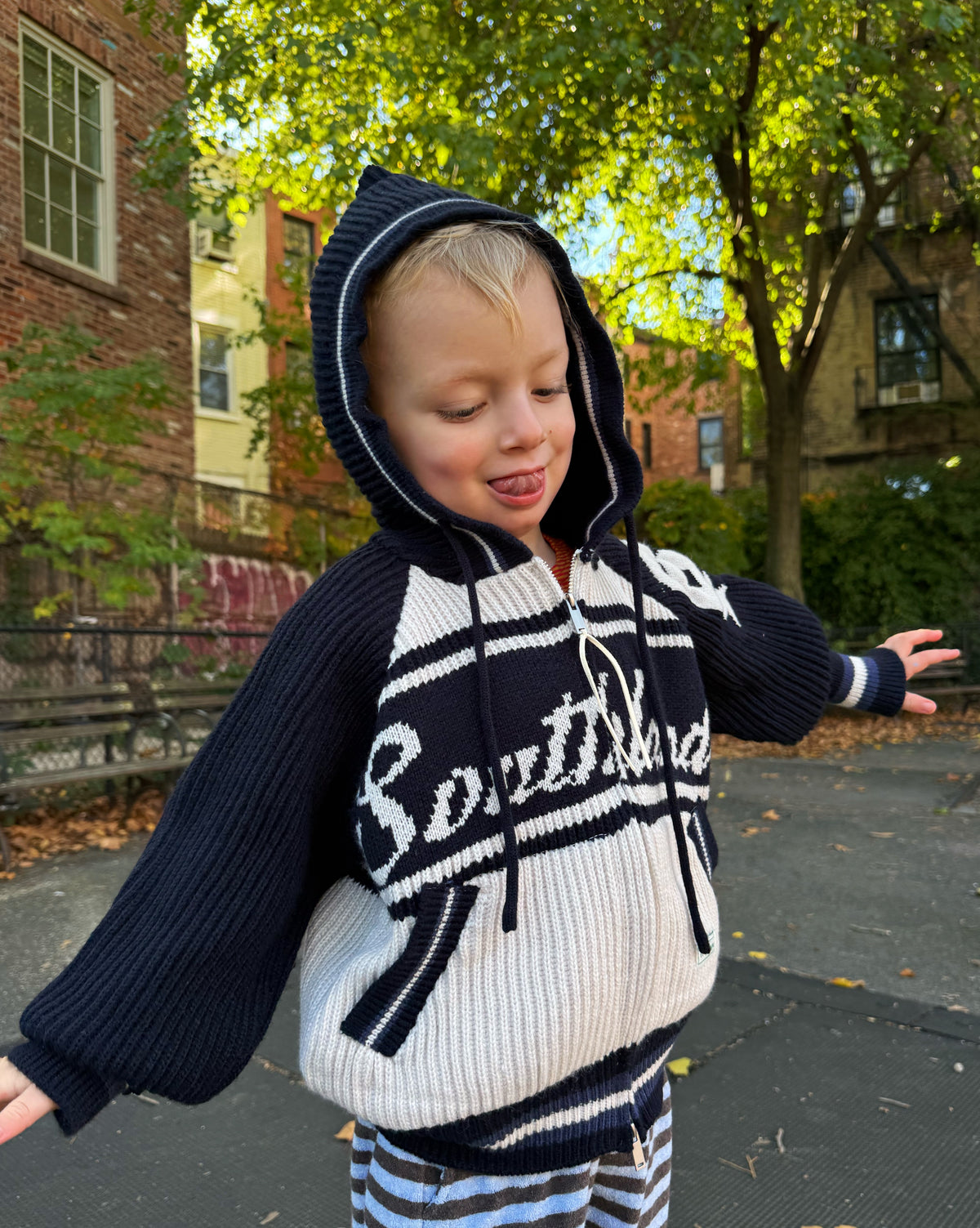 Child wearing a navy and white sweater with 'Southend' printed on it, standing outdoors.
